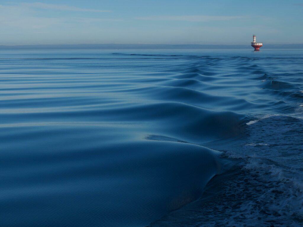 Calm St. Lawrence River with distant Haut-Fond Prince lighthouse and gentle ripples.